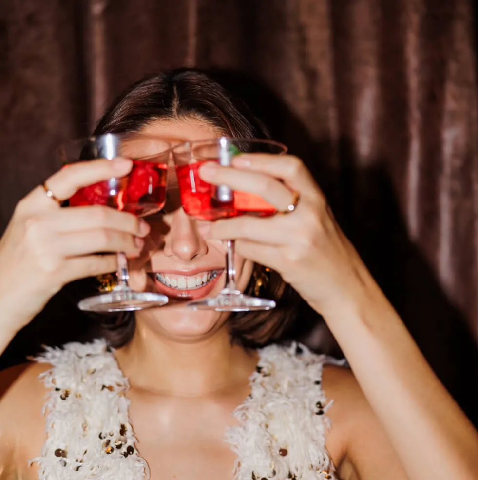 Lady holding up 2 glasses of drinks