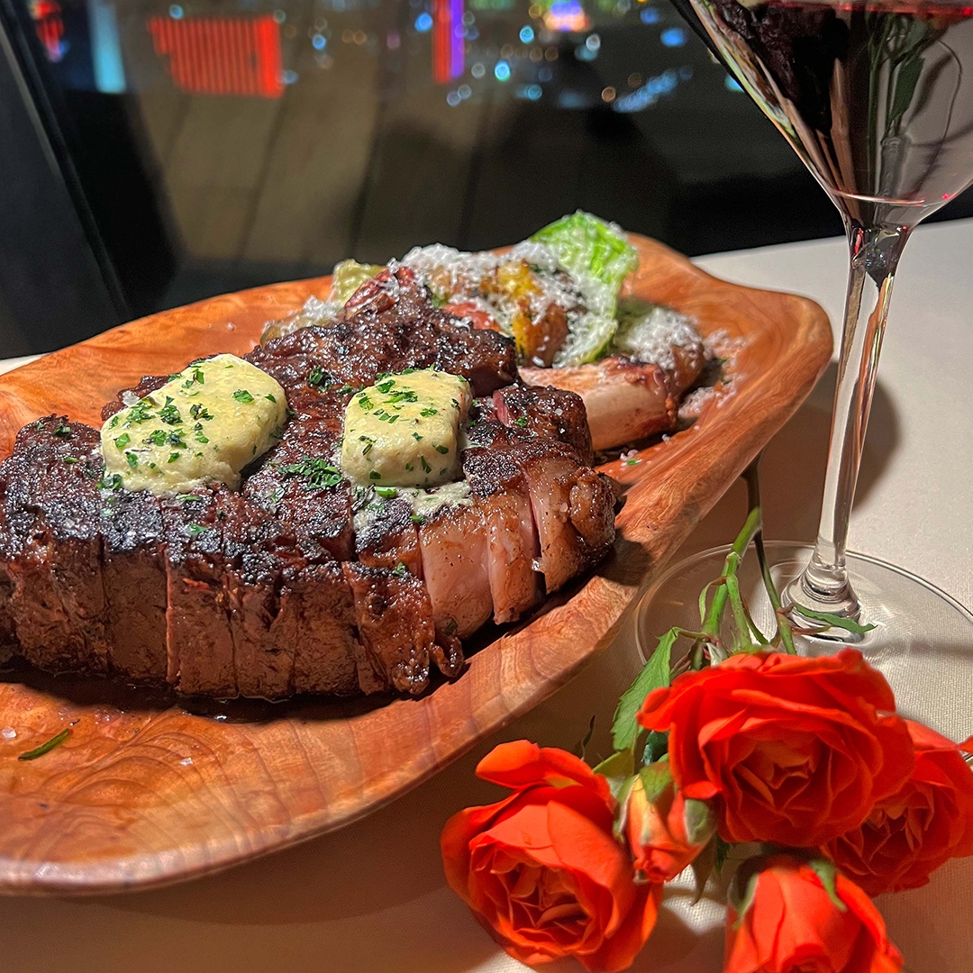 Steak on a plate with a bouquet of roses next to it 