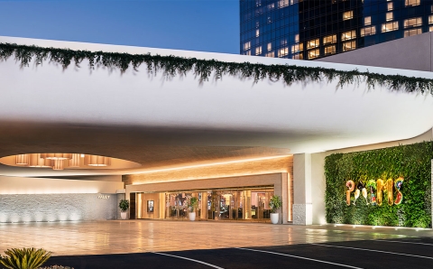 Valet entrance of the Palms Casino Resort in Las Vegas featuring a modern white overhang with greenery, illuminated glass doors, and a vibrant living wall with the Palms sign.